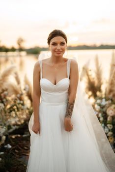 bride against the background of a yellow sunset on a pier near the river