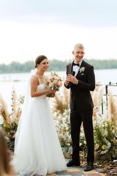 wedding ceremony on a high pier near the river with invited guests