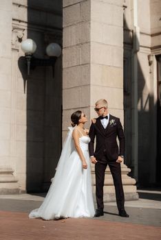 the groom in a brown suit and the bride in a white dress in an urban atmosphere