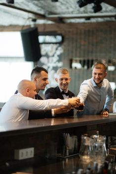 groom in a brown suit and his friends at the bar