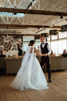 the first wedding dance of the bride and groom inside the restaurant hall in sunset light