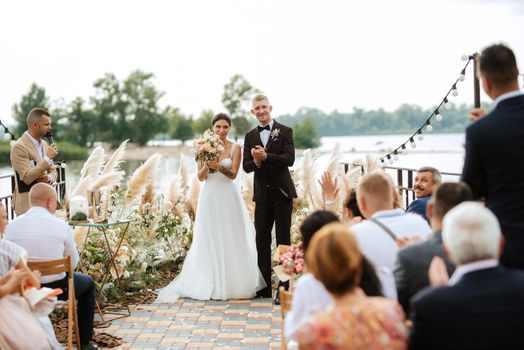 wedding ceremony on a high pier near the river with invited guests