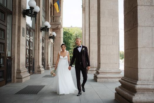 the groom in a brown suit and the bride in a white dress in an urban atmosphere