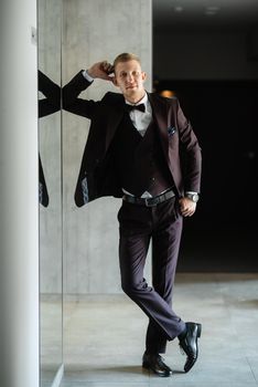 portrait of the groom in a brown three-piece suit with a bow tie on the wedding day