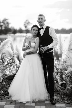 bride and groom against the backdrop of a yellow sunset on a pier near the river