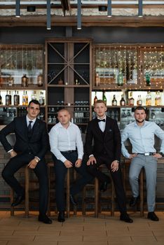 groom in a brown suit and his friends at the bar