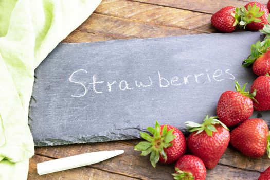 Fresh strawberries and a chalkboard sign with strowberries written on it