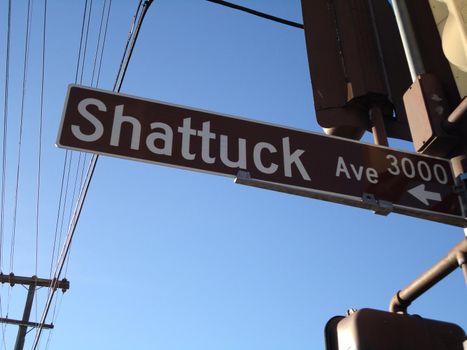 Shattuck Ave Street sign in Berkeley attached to streetlights with powerlines overhead.