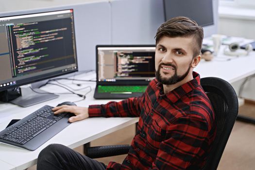 Senior developer working on computer in IT office, sitting at desk and coding, working on a project in software development company or technology startup.