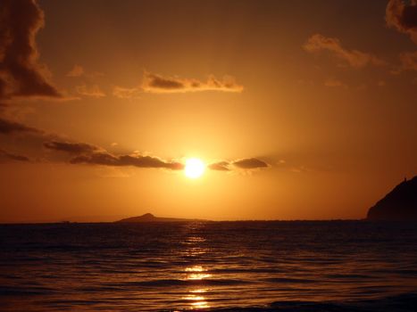Sunrises over Kaohikaipu (Black/Turtle) Islands with the Maka'Pua lighthouse and Molokai visible in the distance.