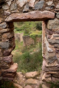Jinquer, Castellon, Spain. Houses in ruins of an abandoned village in the middle of the vegetation.Mountain, group of houses. roads, Spanish Civil War