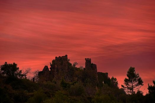 Jinquer, Castellon Spain. Ruins of abandoned castle on top of mountain Mediterranean forest, olive trees, pines, sunset sky warm and orange colors