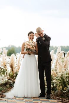 wedding ceremony on a high pier near the river with invited guests