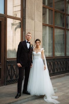 the groom in a brown suit and the bride in a white dress in an urban atmosphere