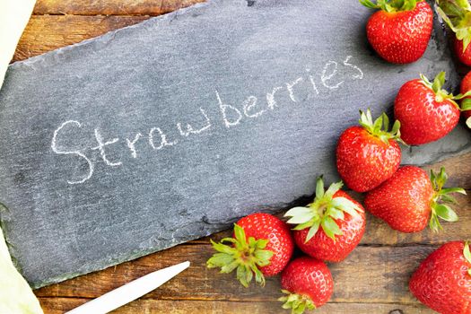 Fresh strawberries and a chalkboard sign with strowberries written on it