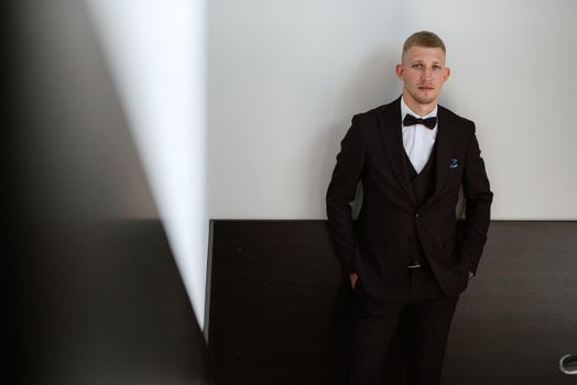 portrait of the groom in a brown three-piece suit with a bow tie on the wedding day