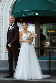 bride and groom near the cafe on the street of the summer city