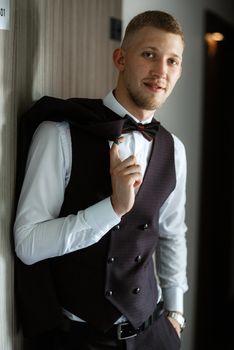 portrait of the groom in a brown three-piece suit with a bow tie on the wedding day