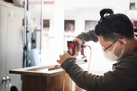 Entrepreneur Woodwork holding a Tacker to assemble the wood pieces as the customer ordered