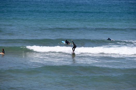 Guipuzkoa, Zarautz, Spain - 09, July, 2022: Group of surfers on the beaches of Zarautz. Group of surfers, enjoying their sport, surfing taking advantage of the good weather on the coast of the Basque Country