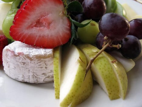 Close-up of Fruit and Cheese on a white plate.  Featuring Strawberries, grapes, pears slices