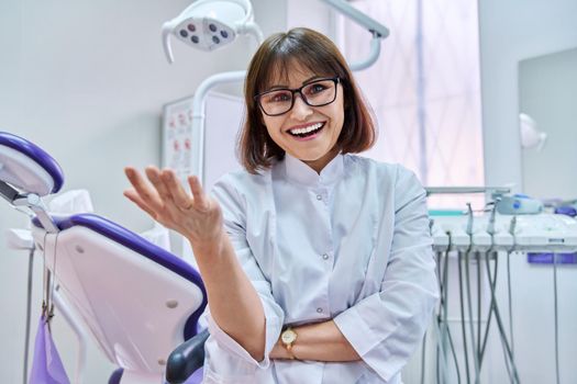 Talking consulting female doctor dentist looking at webcam, making video call chat conference, in dental office. Online technology, telemedicine, help, medicine, health care concept