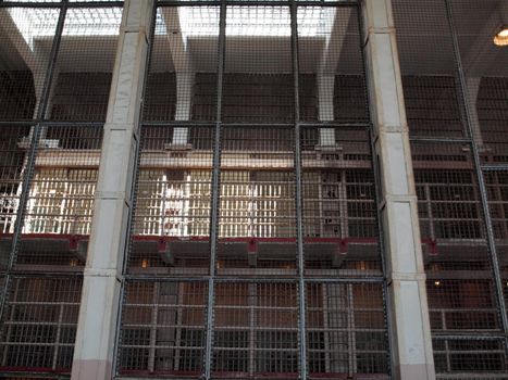 Cage of bars with cell blocks behind them inside Alcatraz prison.