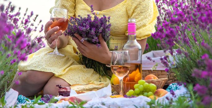 A woman drinks wine in a lavender field. Selective focus. Food.