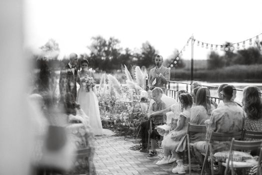 wedding ceremony on a high pier near the river with invited guests