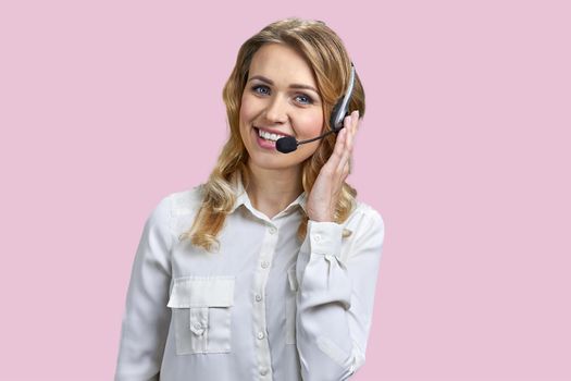 Portrait of beautiful call center operator on pink background. Woman with headset talking to someone online.