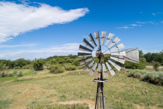 old fasion rustic wind pum or wind mill that is in use.