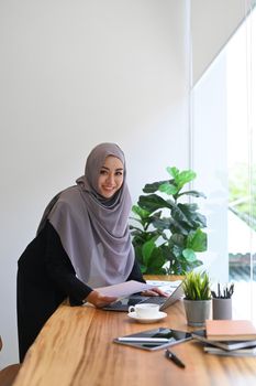 Muslim business woman working with charts, statistics and data at bright modern office.