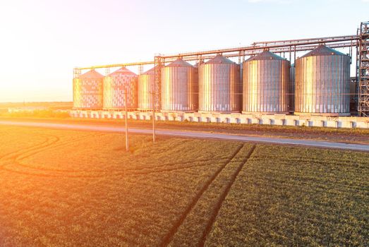 Grain elevator. Metal grain elevator in agricultural zone. Agriculture storage for harvest. Grain silos on green nature background. Exterior of agricultural factory