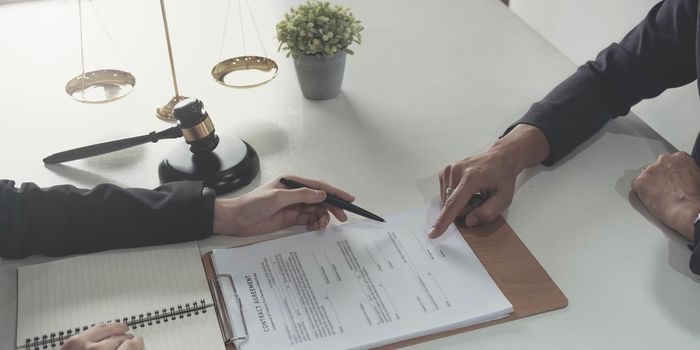 business people working together at meeting in modern office, close-up. Businessman and woman with colleagues or lawyers discussing contract at negotiation.