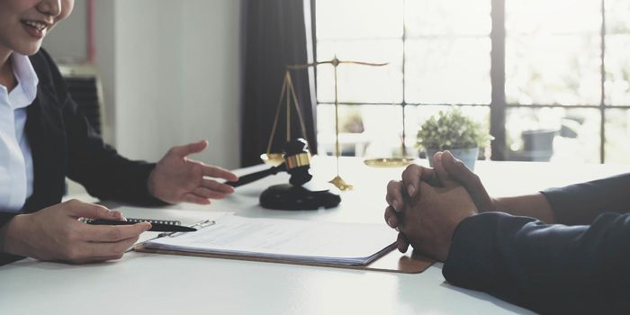 Business woman and lawyers discussing contract papers with brass scale on wooden desk in office. Law, legal services, advice, Justice concept..