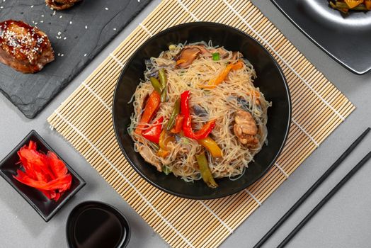 food Asian cuisine. Asian or Szechuan noodles. Chinese wok noodles in a bowl with vegetables and teriyaki chicken.