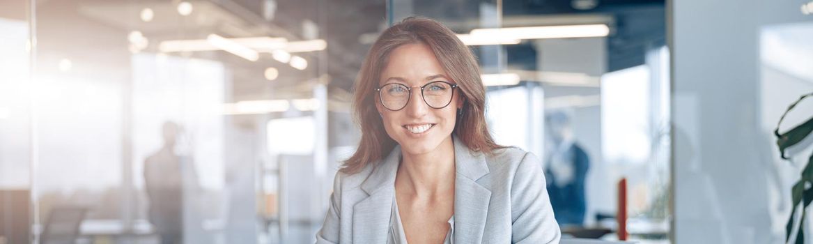 Portrait of smiling businesswoman working on laptop at her workplace at modern office.