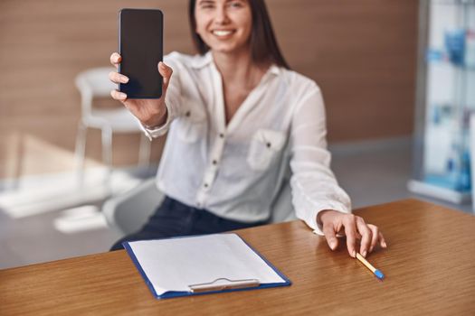 Happy smiling caucasian woman with phone and documents in modern clinic reception