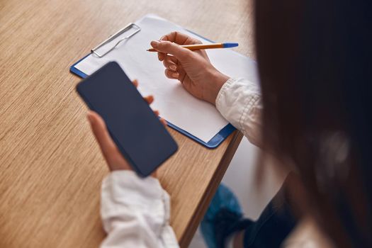 Happy smiling caucasian woman with phone and documents in modern clinic reception