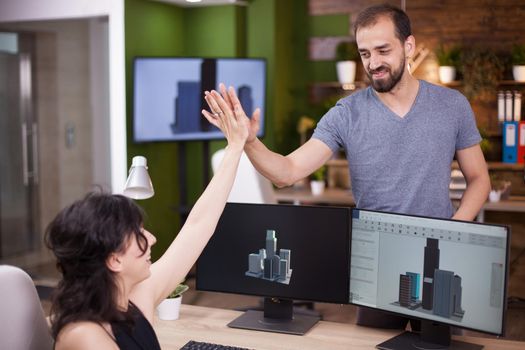 Two young collegues happy about their project give a hi5 in their office. Business partners in their office.