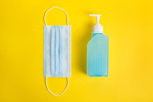 protective mask and disinfectant gel on a yellow background, concept of new normality and protection against viruses