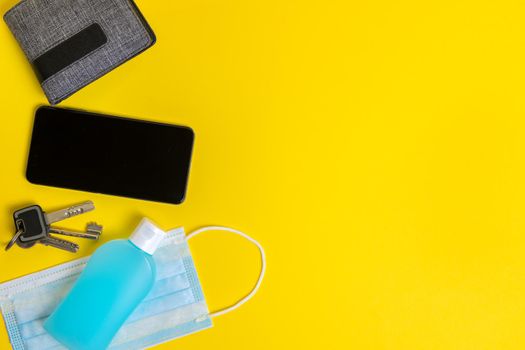 objects needed to go out in the new normal, protective mask, disinfectant gel, keys, wallet and phone on a yellow background, concept of protection against viruses, copy space for text