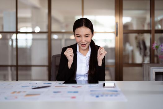 Excited young asian business woman celebrating successful financial project results, attracting important corporate client, dream goal achievement