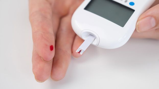 Woman measures blood sugar level with a glucometer