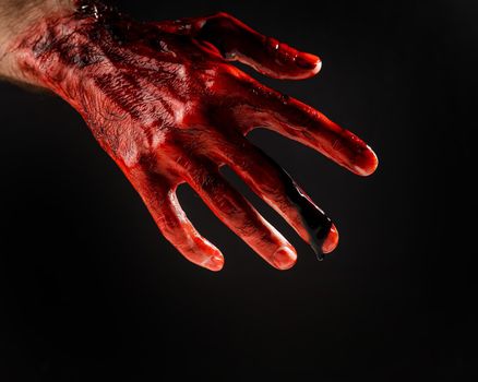 Close-up of a male hand stained with blood on a black background