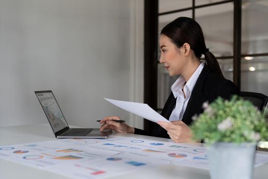 Portrait of Young Successful Asian Businesswoman Sitting at Desk Working on Laptop Computer in Office. Ambitious Corporate Manager Plan Investment Strategy for e-Commerce Project