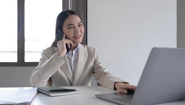 Young asian businesswoman beautiful charming smiling and talking on the mobile phone in the office..