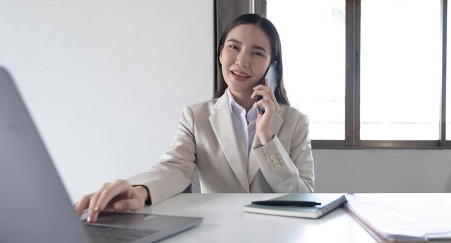 Young asian businesswoman beautiful charming smiling and talking on the mobile phone in the office..