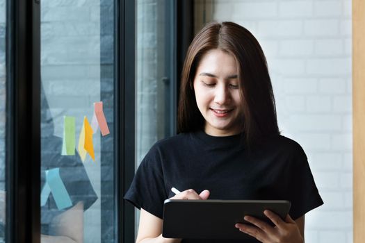 A female company employee uses a tablet and notepad to analyze company budgets