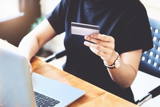 Online payment with Young Women hands holding credit card and using computer for online shopping.